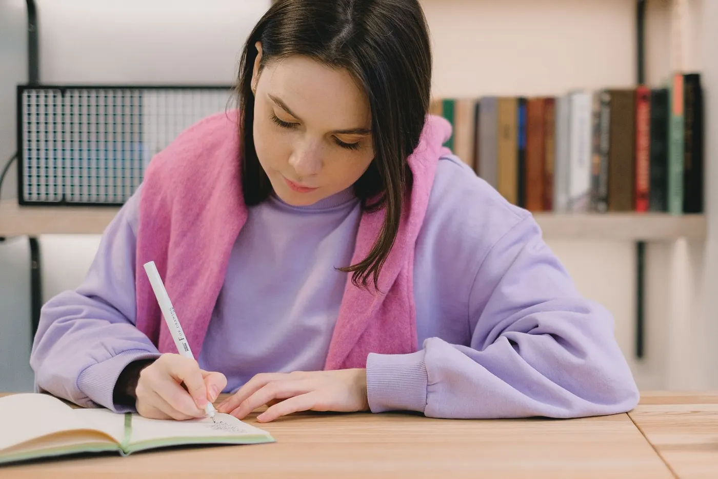 A student writing notes at a library desk